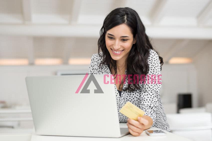 Happy young woman holding a credit card and shopping online at home. Beautiful girl using laptop to shop online with creditcard. Smiling woman using laptop and credit card for online payment.